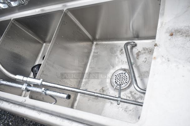Commercial 3 bay sink with dual drain boards, stainless steel, used condition, visible pipes and drainage fittings.