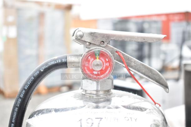 Close-up of a fire extinguisher with pressure gauge, labeled "Overcharged." Metal handle and attached hose. Buyer must pick up.