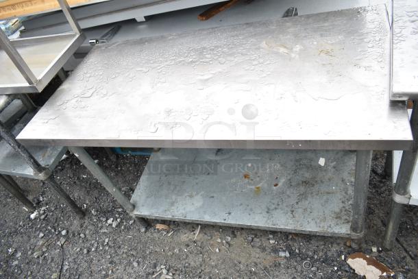 Commercial stainless steel table with under shelf, showing signs of wear and outdoor exposure.
