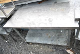 Commercial stainless steel table with under shelf, showing signs of wear and outdoor exposure.
