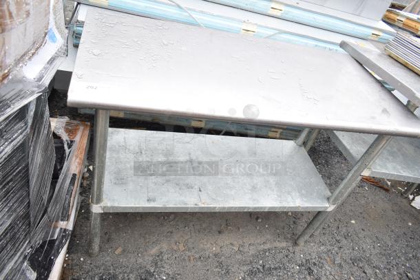 Stainless steel commercial table with under shelf, used condition, visible surface wear, no visible markings.