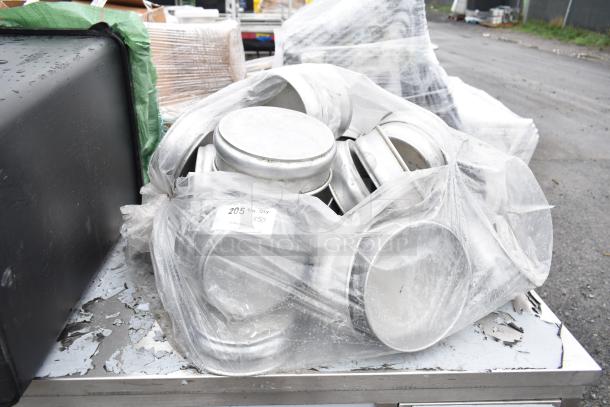 Plastic-wrapped bundle of 50 round baking pans, slightly scratched, with a label reading "205 4¾ QTY x50" on a metal surface.