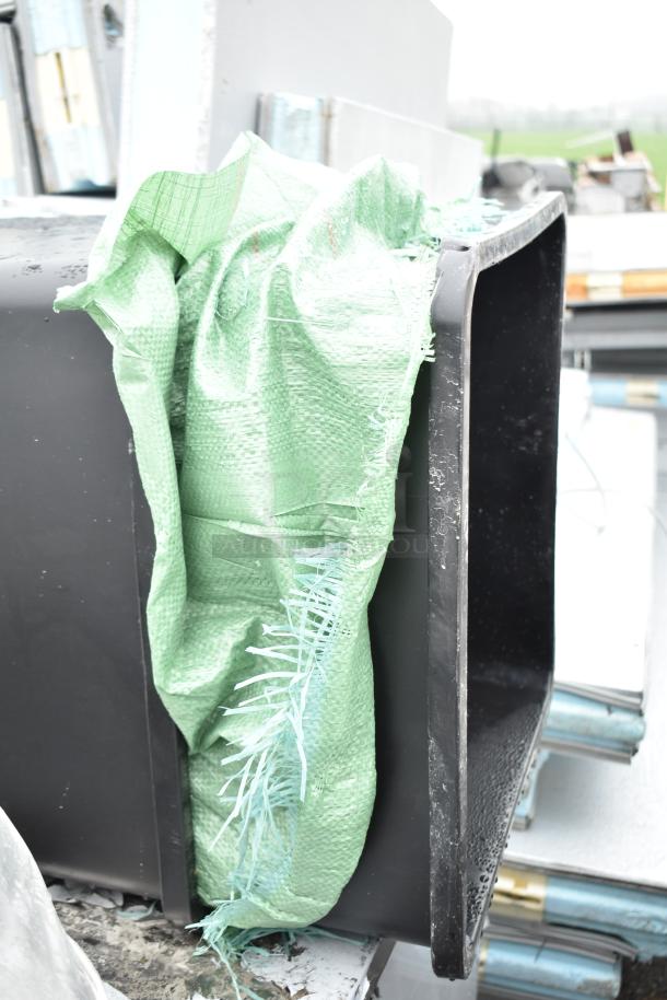 Two black poly trash cans, stacked with green tarp. Rugged design, suitable for heavy-duty waste management. Auction lot offers double your bid.