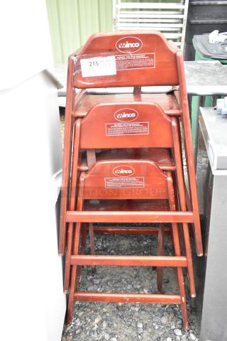 Three Winco wooden high chairs stacked. Sturdy design, natural wood finish, safety harness, some wear visible.