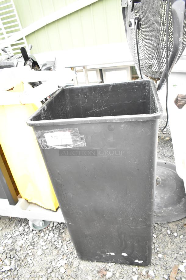 Black poly trash can in fair condition, minor surface scratches. Label with undecipherable markings. Ideal for industrial use.