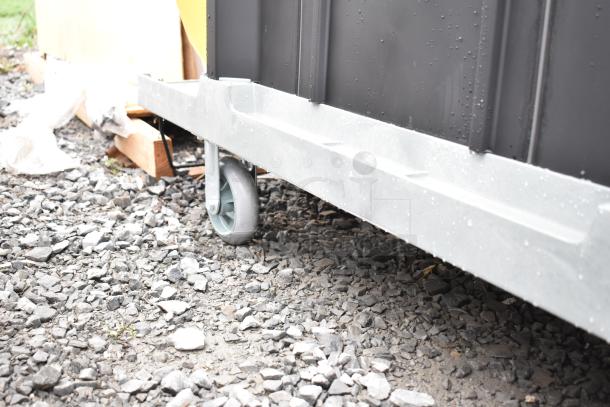 Lavex Janitorial Cart featuring sturdy commercial casters for easy maneuverability, visible on rocky terrain, good condition.