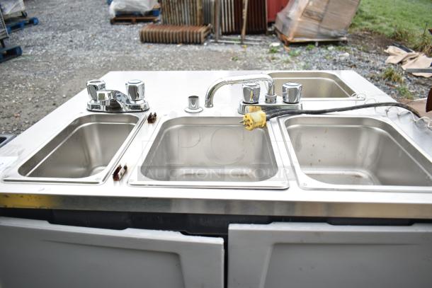 Stainless steel portable sink with three basins and chrome faucets. Includes power cord. Slight wear visible.