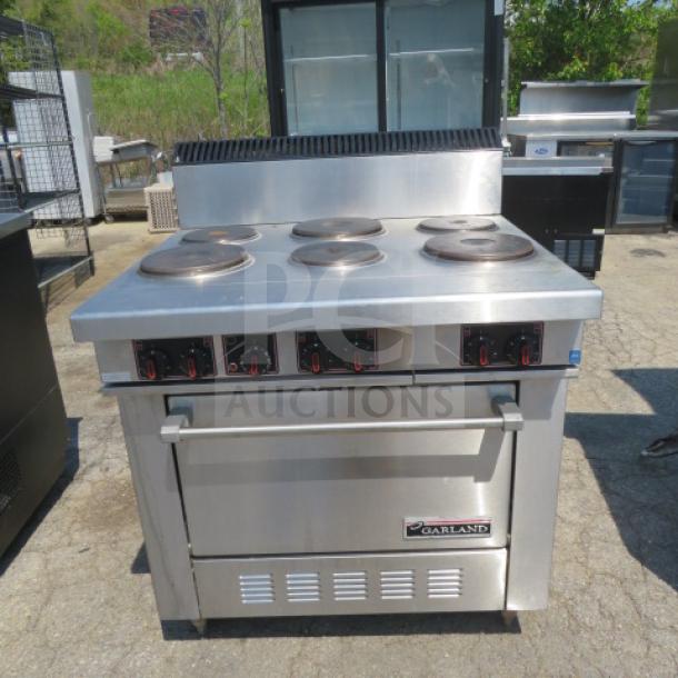 Garland natural gas 6-burner range in stainless steel, featuring control knobs and lower storage. Good condition.