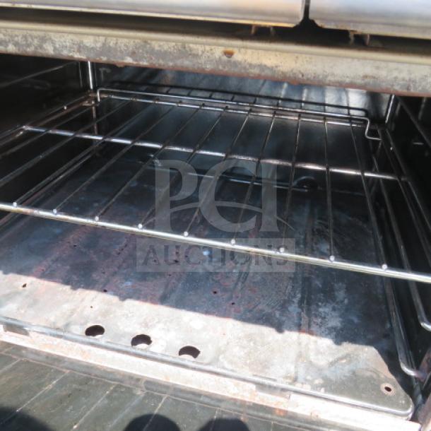 Garland natural gas 6 burner range oven interior, featuring metal racks and visible wear. Ideal for commercial kitchens.