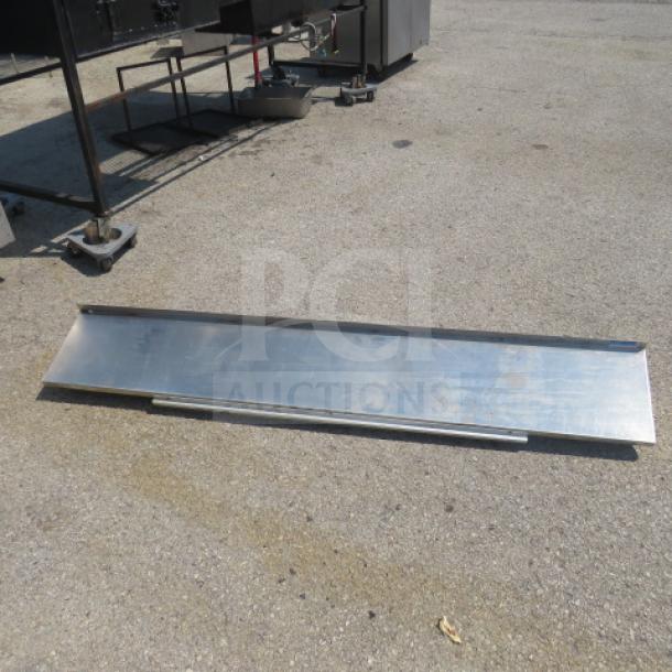 Stainless steel wall mount shelf, 72x12x10 inches, includes 1 bracket and 44-inch ticket rail attached, shown outdoors.