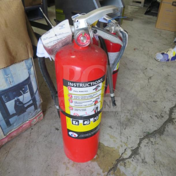 Badger ABC fire extinguisher, red, includes instructions label. Silver nozzle, black hose. Good condition.