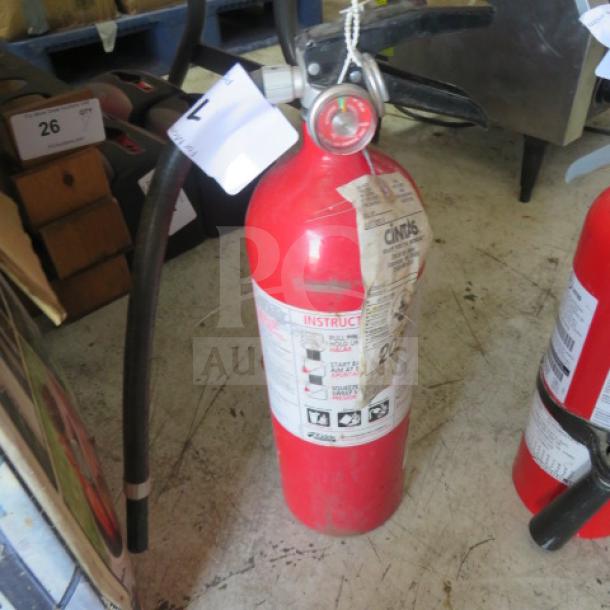 Kidde ABC fire extinguisher, cylindrical red body, visible instructions, black hose, good condition.