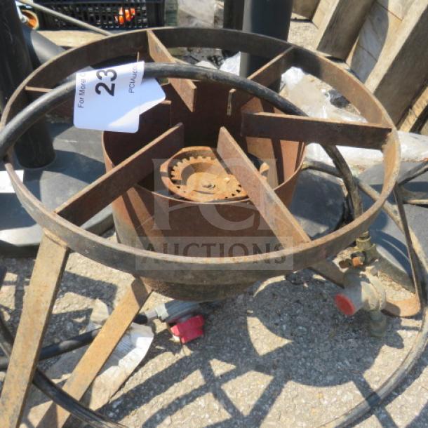 Rustic one gas burner with circular metal frame, visible rust, and an attached valve. Auction tag marked "23." Suitable for outdoor use or restoration.