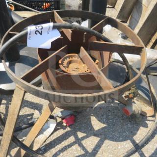 Rustic one gas burner with circular metal frame, visible rust, and an attached valve. Auction tag marked "23." Suitable for outdoor use or restoration.