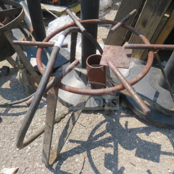 Rustic single gas burner with metal frame, showing wear and patina. Lacks visible branding or model info.