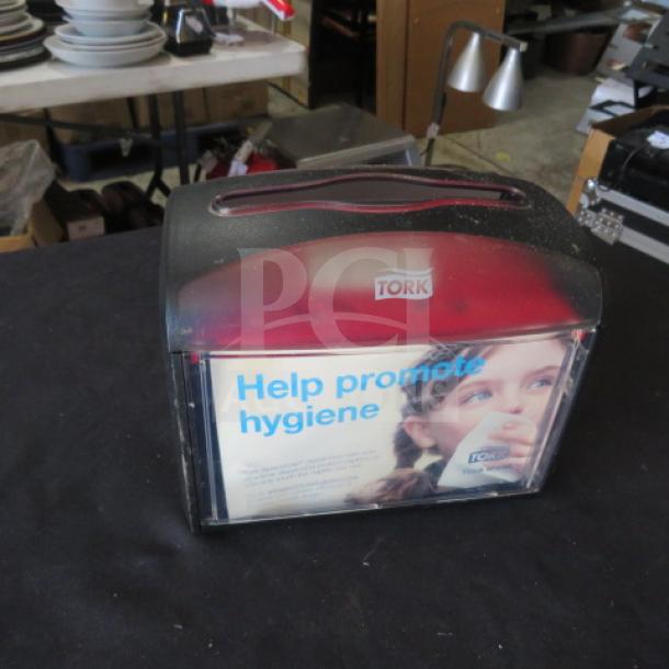 Tork Table Top Napkin Dispenser, red and black, with promotional hygiene message. Used condition, clear front panel.