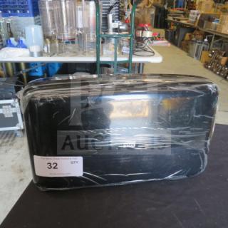 Black Tork toilet paper dispenser, wrapped in plastic, showing a label with auction lot number 32.