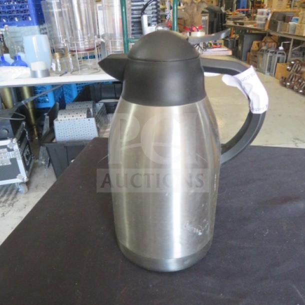 Stainless steel creamer/coffee pot with black handle and lid, good condition, visible tag on handle.