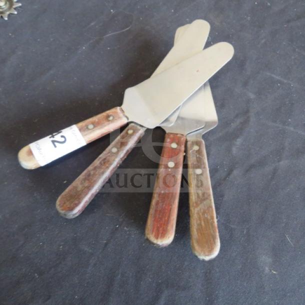 Set of three pizza/pie servers with wooden handles and stainless steel blades. Displayed in used condition.