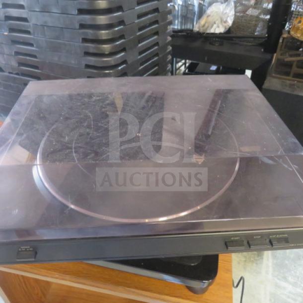 Sony turntable with clear dust cover, showing minor surface scratches. Control buttons visible on the front panel.