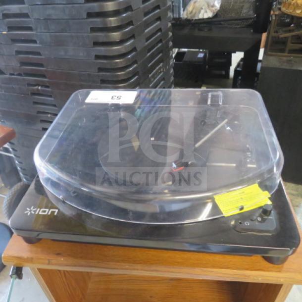 Ion turntable with clear dust cover, black base, rotary dial. Model unidentified, in used condition, partially visible yellow tag.