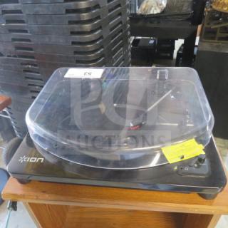 Ion turntable with clear dust cover, black base, rotary dial. Model unidentified, in used condition, partially visible yellow tag.
