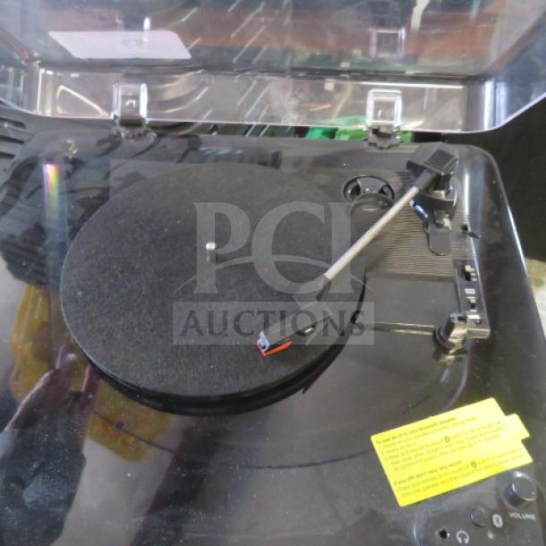 ION turntable with dust cover, black, in good condition. Features include tonearm and platter. Yellow label with instructions visible.