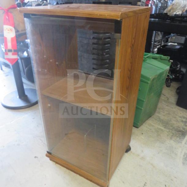Wooden media case with glass door, 18x16x38 inches. Features adjustable shelves and CD slots. Good condition.
