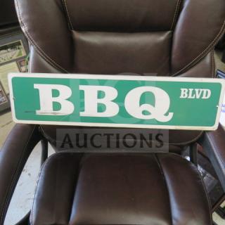24x6 inch "BBQ BLVD" street sign with green background and white lettering, minor wear, displayed on a brown chair.