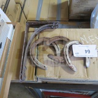 Lot of miscellaneous metal items, including rusted metal brackets and horseshoes. Items show signs of wear. Tag with "64" visible.