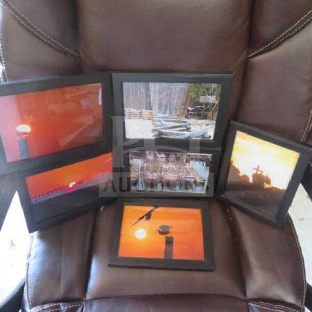 Assorted framed pictures featuring nature and sunset scenes, set of six. Black frames, displayed on a brown chair.
