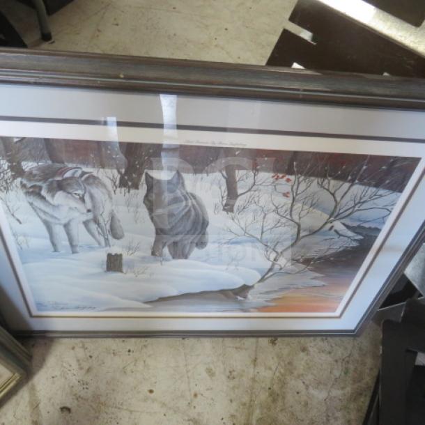 Framed artwork of wolves in a snowy landscape, featuring two wolves, one black and one grey, near a stream at sunset.
