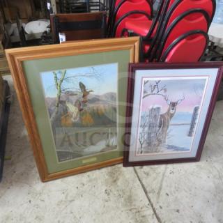 Two framed wildlife paintings, one depicting ducks in flight with a wooden frame, and another of a deer in snow with a dark frame.