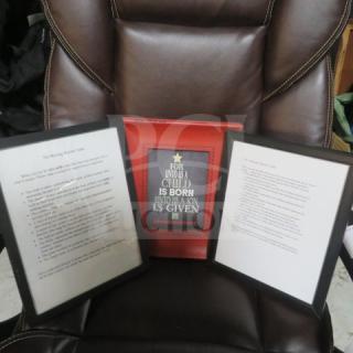 Assorted decor items with two framed writings and a red plaque featuring a quote on a leather chair, good condition.