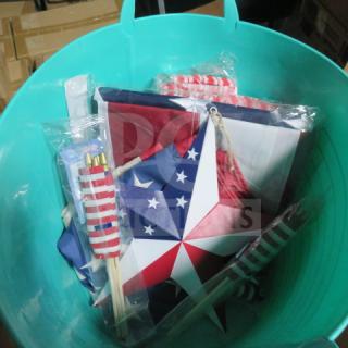 Miscellaneous patriotic items in a green plastic bucket, including mini flags, a star decoration, and other themed accessories.