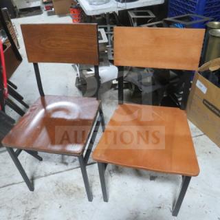 Pair of black metal chairs with wooden seats and backs, model 4XBID, in good condition.