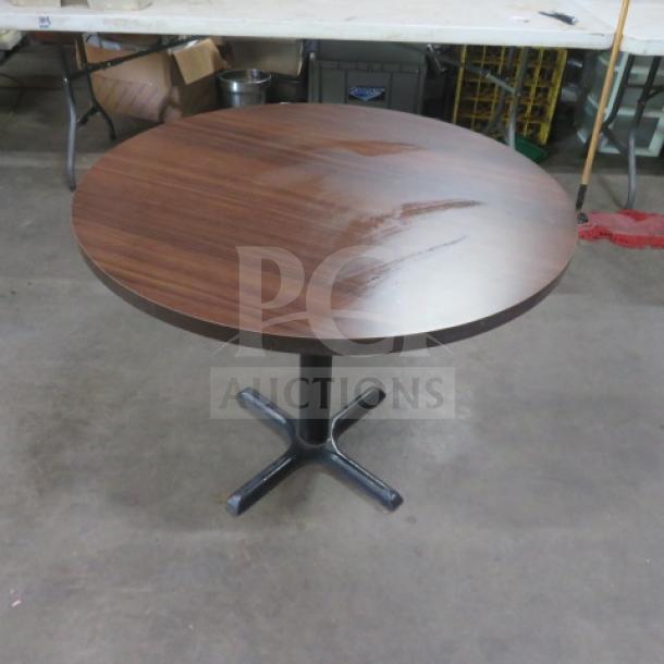 Brown laminate round table with pedestal base, measuring 32x32x30 inches. Good condition, ideal for dining or office use.
