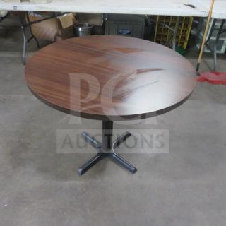Brown laminate round table top on pedestal base, 32x32x30 inches. Appears in good condition, ideal for dining or office use.
