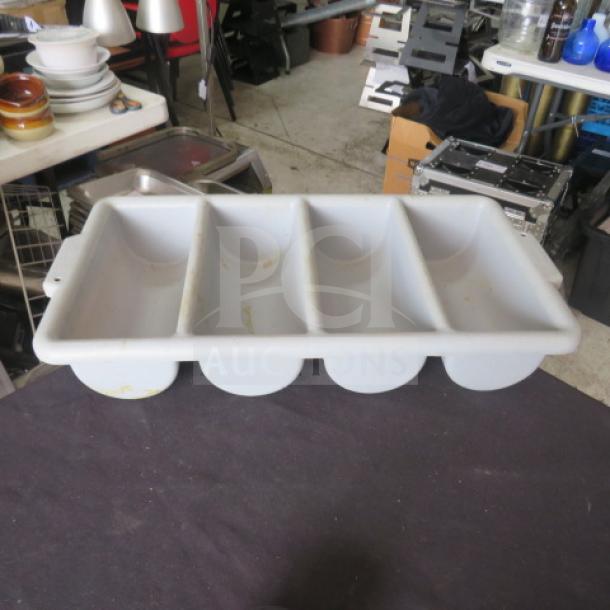 White plastic flatware holder, four compartments, visible wear and stains, rectangular shape, used condition.