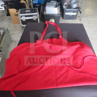 Lot of 6 red aprons displayed on a table, in excellent condition. Bright red color with neck and waist ties, no visible tags.