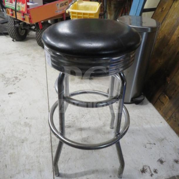 Black cushioned bar stool with two chrome rings, in good condition.