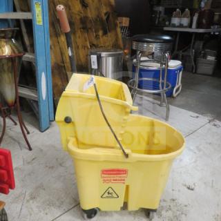 Rubbermaid yellow mop bucket with wringer, visible caution symbol, on casters, used condition.