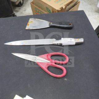 Assorted utensils: a putty knife with a black handle, a kitchen knife with a patterned handle, and red-handled scissors. Visible wear on knife blade.