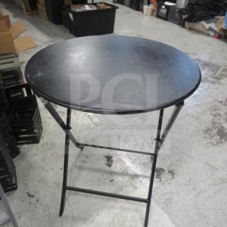 Black metal foldable table, round top, 24x28.5 inches. Used condition, sturdy frame, compact storage design.