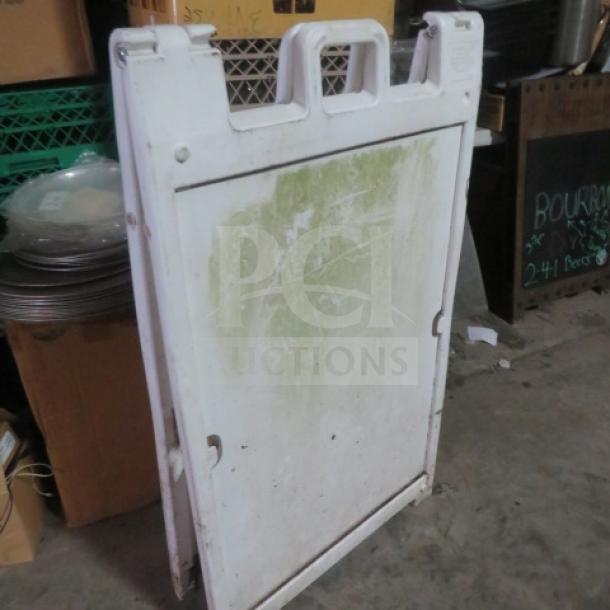 White Signcade sidewalk sign with green discoloration on front. Used condition with a handle on top; suitable for advertising.