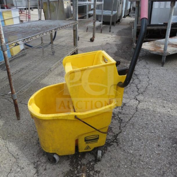 Yellow mop bucket with wringer, black handle, on wheels; shows wear. Suitable for commercial cleaning duties.