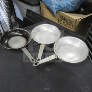 Three 7.5-inch sauté pans with metal handles; two in fair condition and one heavily used. No visible brand markings.