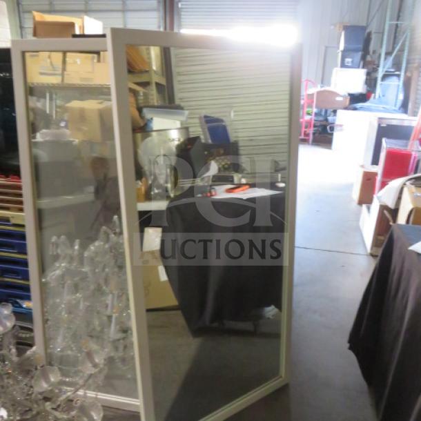 Framed mirror, 30x60 inches, in a storage setting. Rectangular with a simple frame, in good condition.