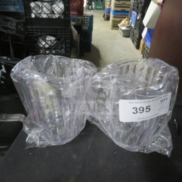 Two new clear plastic pitchers wrapped in plastic. Auction label reads "395 QTY 2, PCI Auctions."