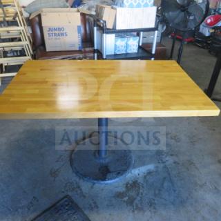 Butcher block table on a sturdy pedestal base, measuring 48x30x30 inches. Light wood finish. Good condition.